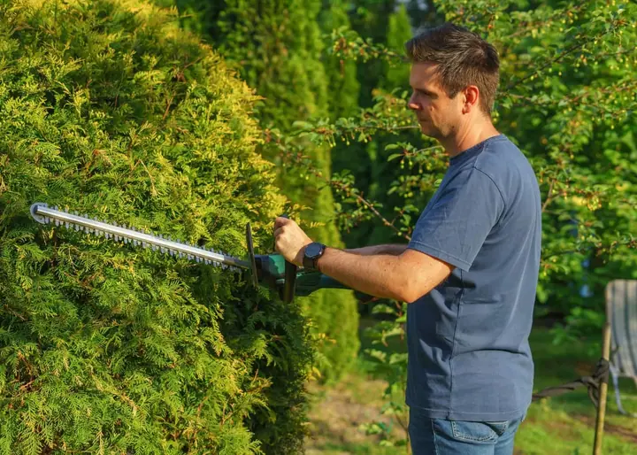 Irrigation technician adjusting a commercial sprinkler head on a landscaped business property
