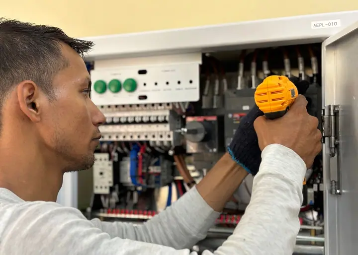 Technician testing elevator controller wiring inside a commercial machine room