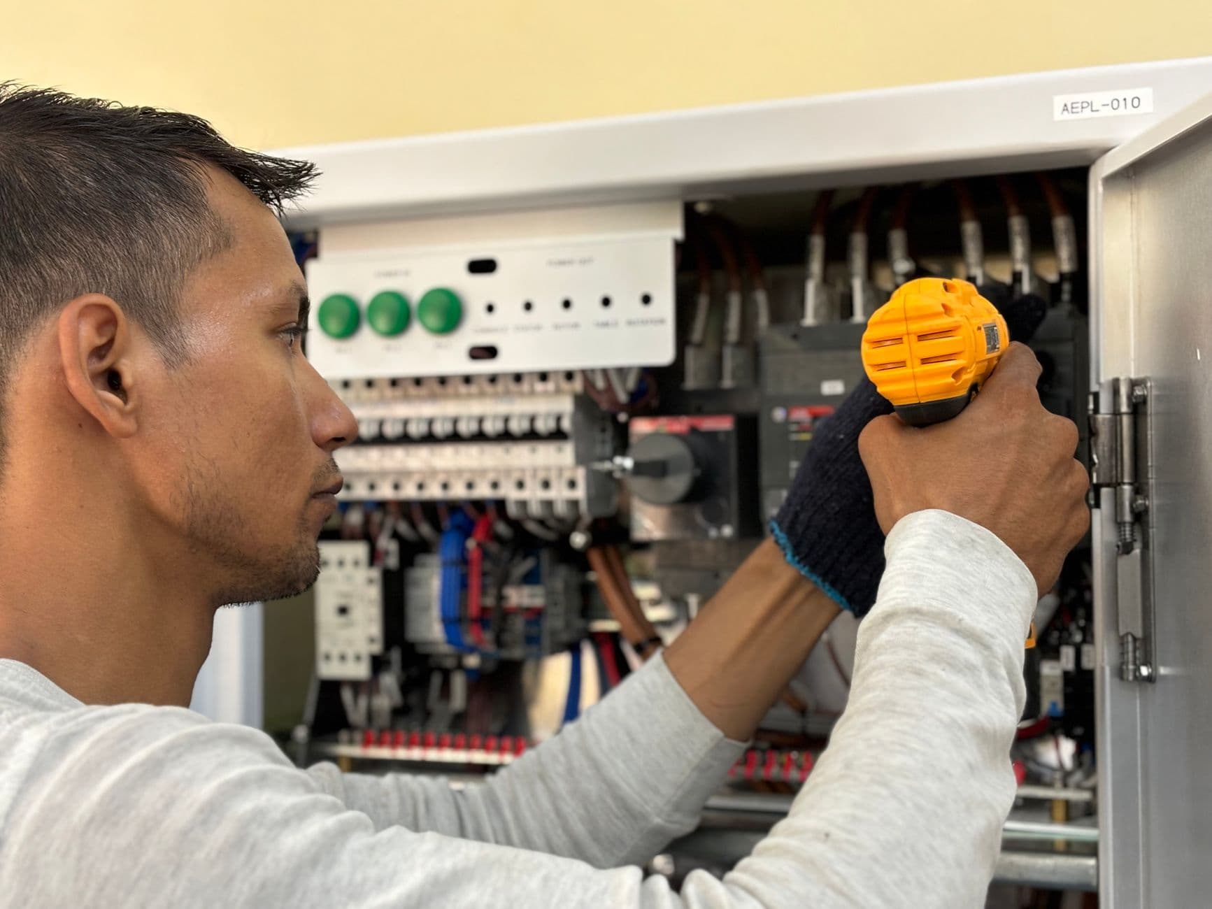 Technician testing elevator controller wiring inside a commercial machine room