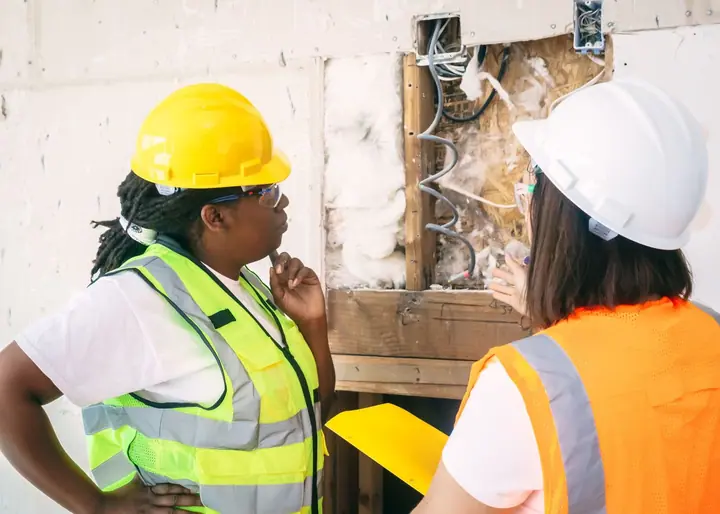 Insulation installer fitting batt insulation between wall studs on a commercial build-out