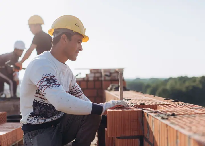 Bricklayer setting concrete block on a commercial jobsite wall