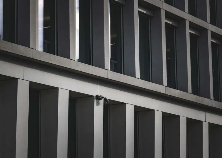 Security guard posted at a commercial building's front entrance while a visitor walks in