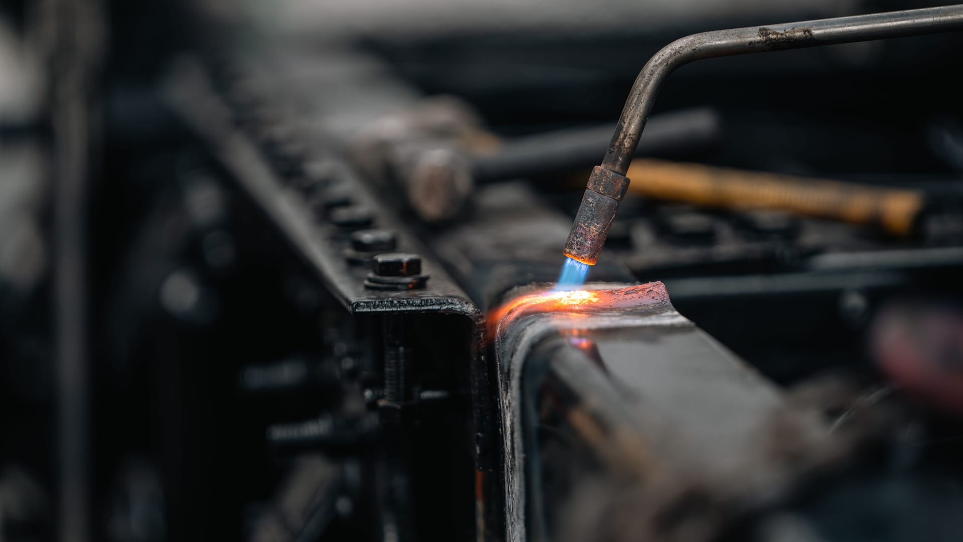 Close-up of a torch cutting a structural steel beam, sparks and blue flame