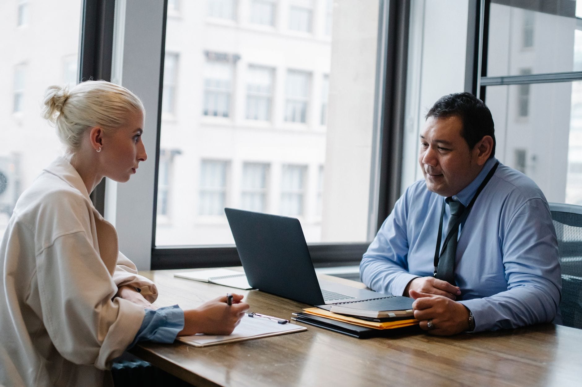 Ethnic boss asking question to female candidate filling information form on clipboard during hiring meeting